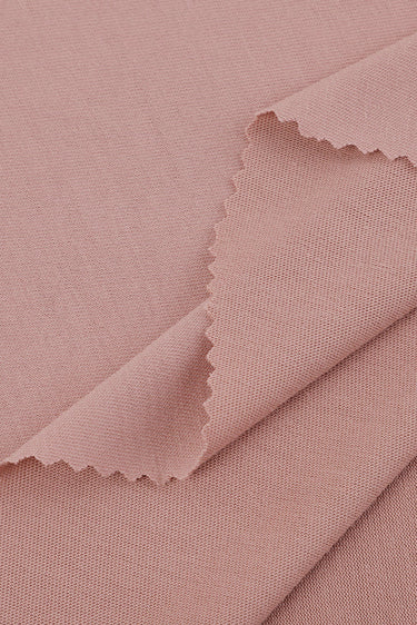 Viscose-covered filament single jersey fabric close-up with layered edge detail and soft drape for lightweight base layers.