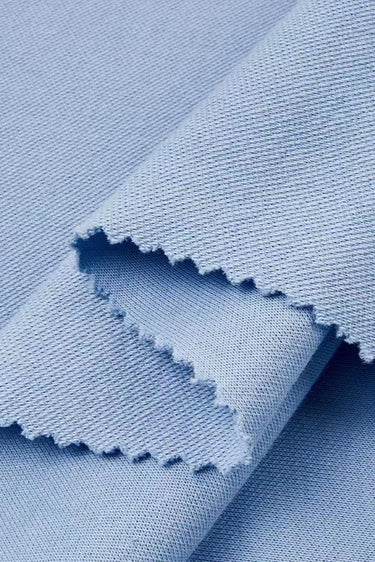 Cotton polyester textured mesh knit fabric close-up with layered edge detail and structured surface for sweatshirts and transitional apparel.