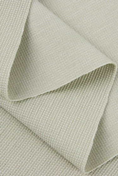 Rayon polyester cotton spandex small jacquard rib knit fabric close-up with layered fold detail and subtle textured surface for modern apparel styles.