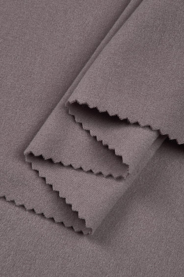 Double-sided stretch knit fabric close-up with layered fold detail for layering garments and cool-season knitwear.