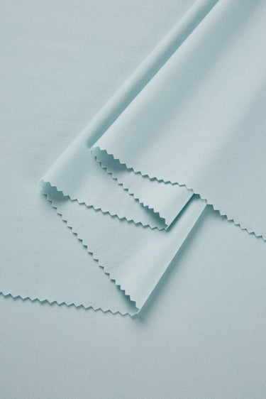 Stretch double knit base fabric close-up with layered fold detail and smooth hand feel for refined everyday apparel.