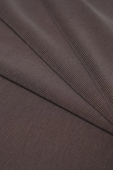 Sand-washed rib knit fabric close-up with diagonal fold detail and matte surface for everyday lifestyle garments.