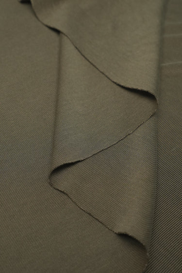 Sand-washed rib knit fabric close-up with layered fold detail for modern knitwear and everyday lifestyle garments.