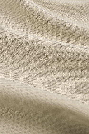 Cotton double knit fabric close-up with surface fold detail and smooth hand feel for breathable everyday apparel.
