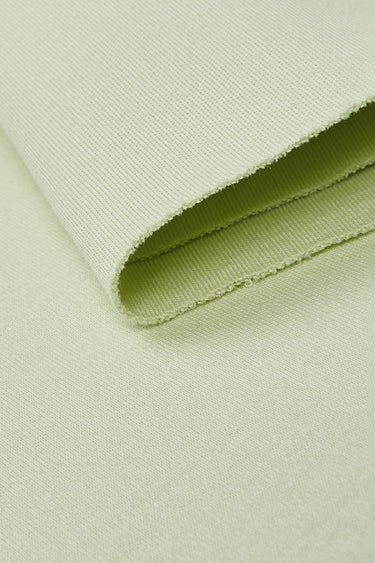 Cotton interlock knit fabric close-up with folded edge detail and stable structure for casualwear and everyday apparel.