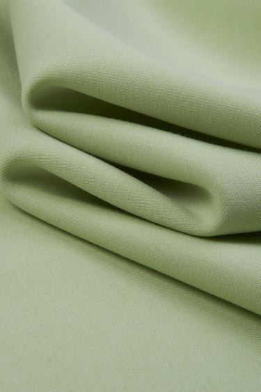 Cotton polyester interlock knit fabric close-up with folded drape detail for transitional apparel and everyday knitwear.