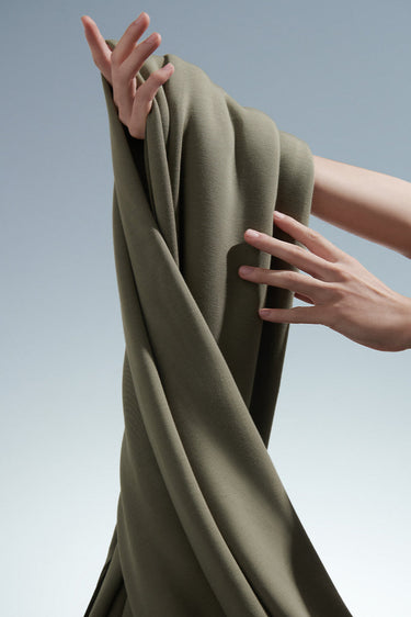Jelly air-layer SCUBA knit fabric shown in a handheld drape view for structured casualwear and modern knit apparel.