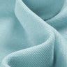 Cotton double piqué knit fabric close-up with curved drape detail and breathable texture for polo shirts and lightweight casual garments.