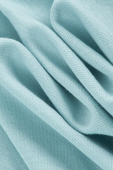 Cotton double piqué knit fabric close-up with folded drape detail and structured surface for lightweight casual garments.