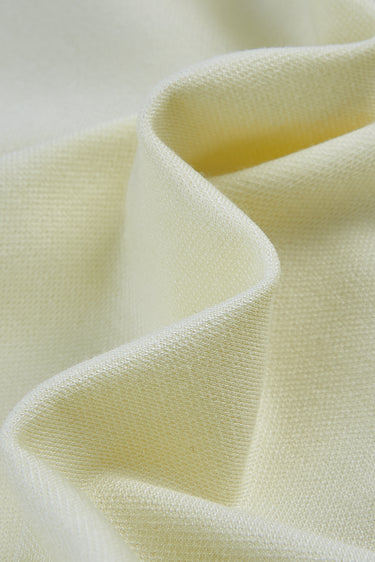 Double-sided piqué knit fabric close-up with curved drape detail and stable structure for modern knit garments.
