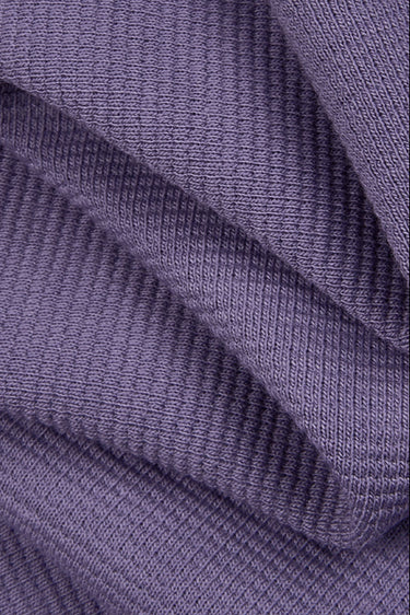 Stretch double-face step knit fabric close-up with folded drape detail and structured texture for refined knit silhouettes.
