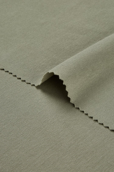 Quick-drying piqué knit fabric close-up with edge structure detail and breathable texture for modern casual garments.