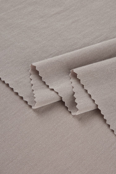 Lenzing TENCEL stretch single jersey fabric close-up with layered fold detail for active daily wear and modern apparel.