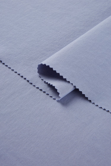 Cotton polyester stretch double knit base fabric close-up with folded edge detail and soft dry touch for casual apparel.