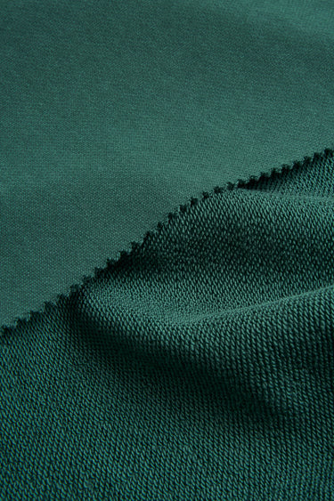 Sand-washed stretch double knit fabric close-up with folded edge detail and smooth hand feel for durable everyday knitwear.