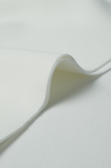 Sand-washed scuba interlock fabric close-up with curved edge detail and soft matte texture for sweatshirts and knitwear.