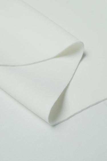 Sand-washed scuba interlock fabric close-up with folded edge detail and refined texture for everyday lifestyle garments.